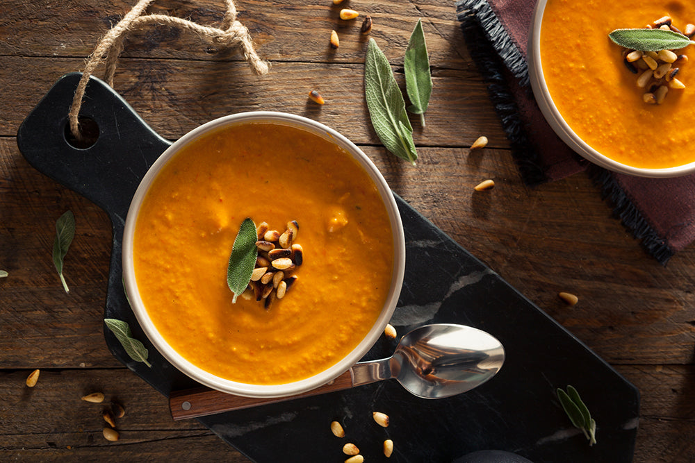 Carrot ginger soup in a bowl garnished with herbs and nuts