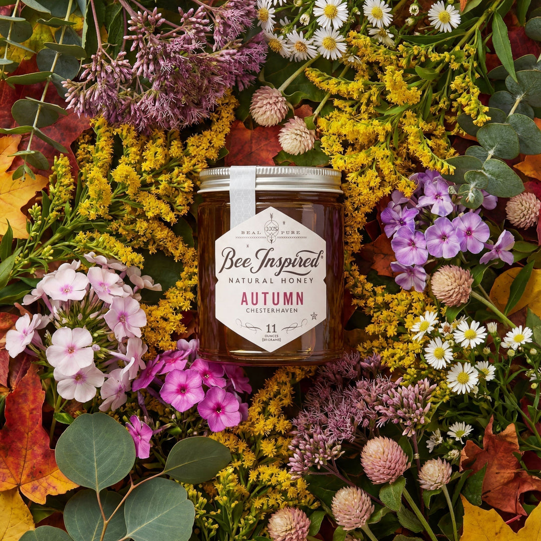 Jar of Bee Inspired Autumn Honey surrounded by autumn flowers and leaves