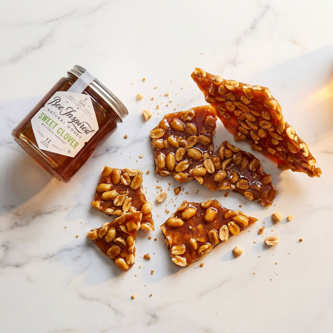 jar of honey next to Honey Peanut Brittle on a white counter