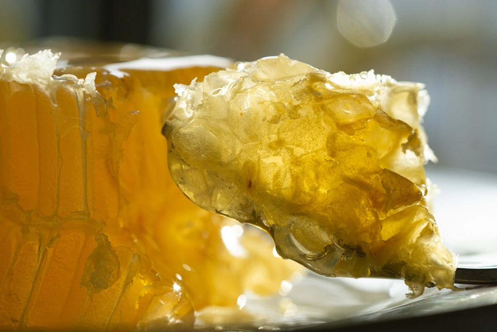 Close-up macro view of honeycomb cells filled with golden honey from Bee Inspired Goods