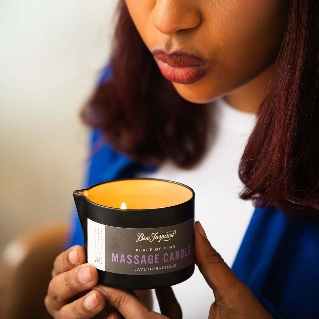 Woman blows out flame of Peace of Mind massage candle 