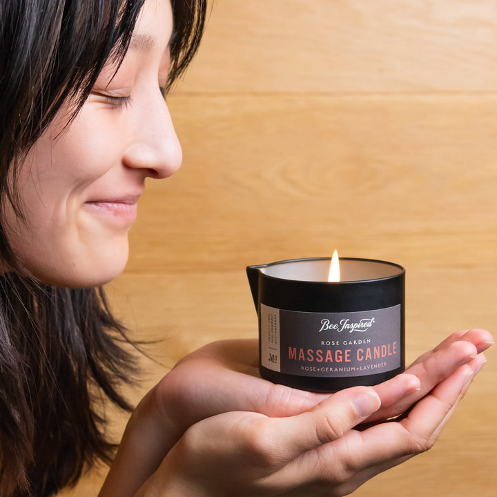 woman holding a lit rose garden massage candle