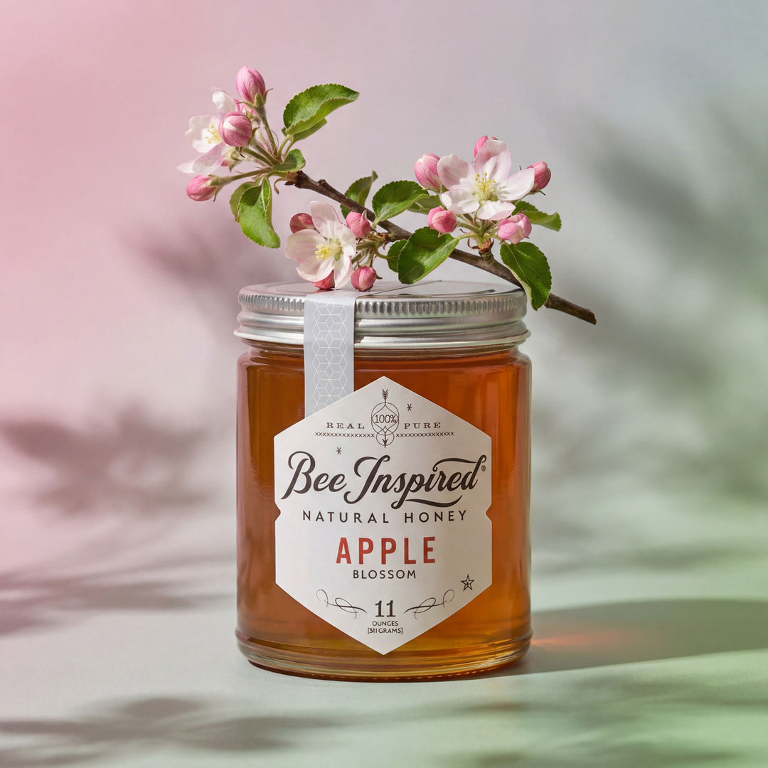 Jar of Bee Inspired natural honey with an apple blossom branch on a blurred background