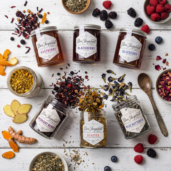 Jars of Bee Inspired honey with various fruits and herbs on a wooden surface