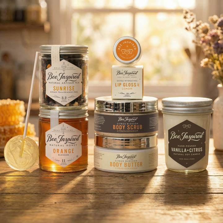 Collection of Bee-Inspired products including tea, lip gloss, body scrub, and body butter on a wooden surface.