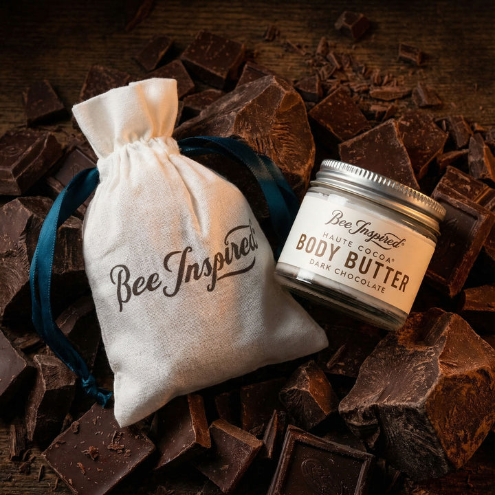 Bee Inspired body butter jar and drawstring bag on a bed of chocolate pieces.