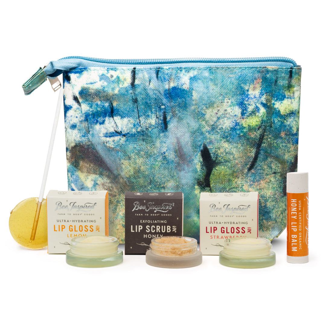 Set of lip care products including lip glosses and scrub with a decorative pouch on a white background.