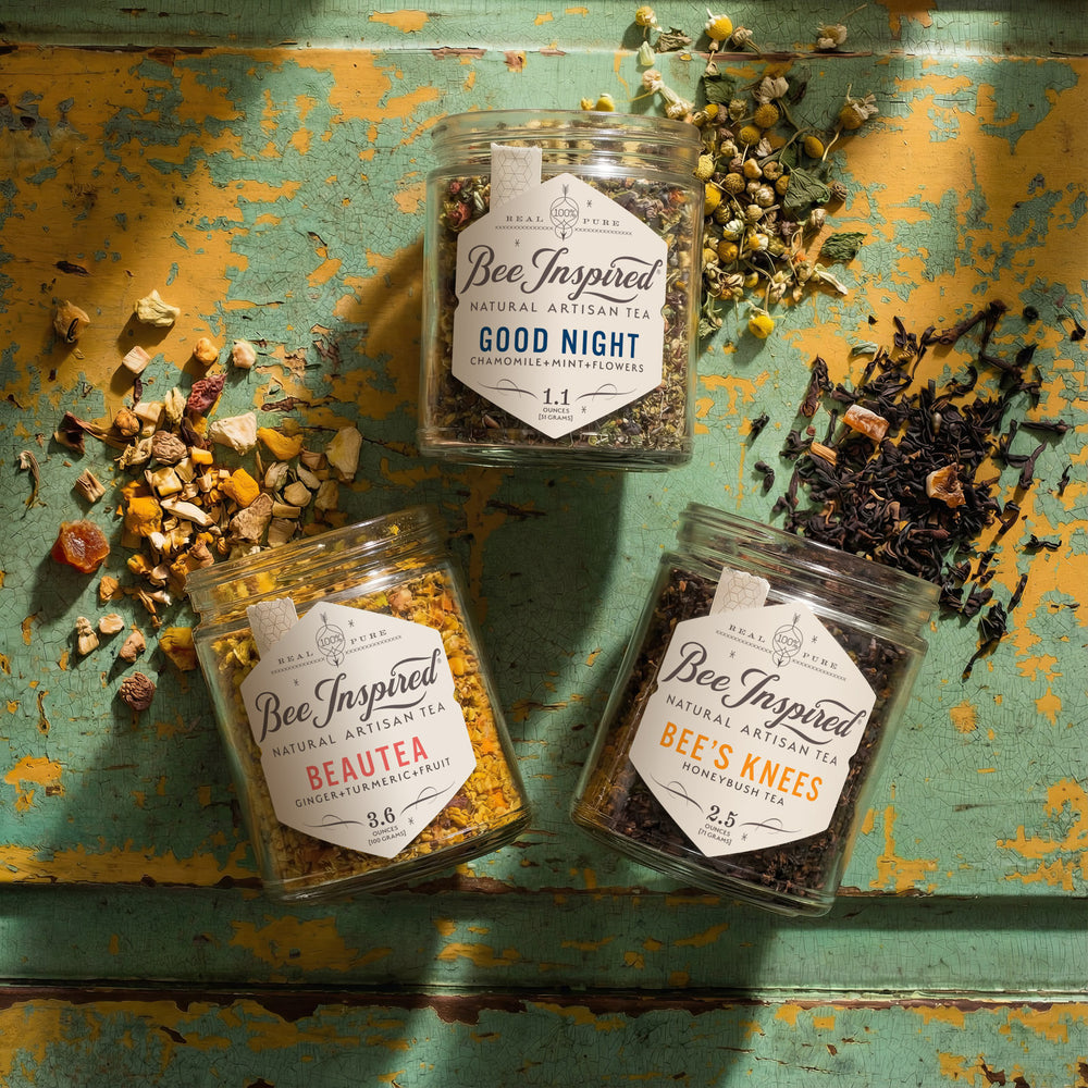 Relaxation Gift Set of 3 jars of 'Bee Inspired' tea on a rustic painted wooden surface with loose leaf tea