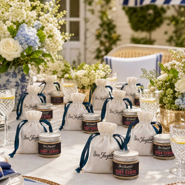 Table setting with Bee Inspired body scrub party favors and white drawstring bags on a decorative tablecloth.
