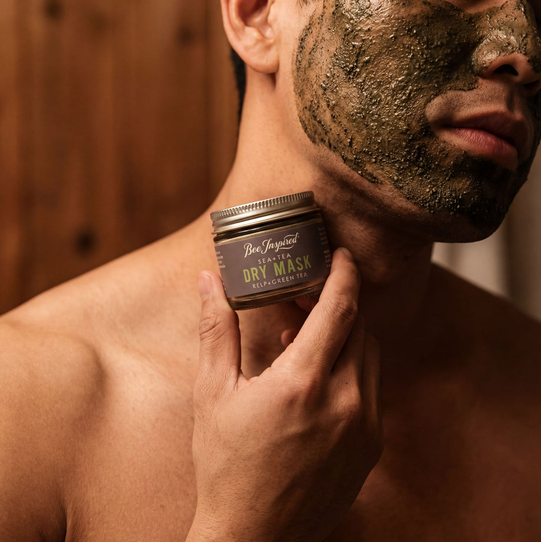 Man applying a dry mask to his face with a Sea+Tea Dry Mask in the foreground.