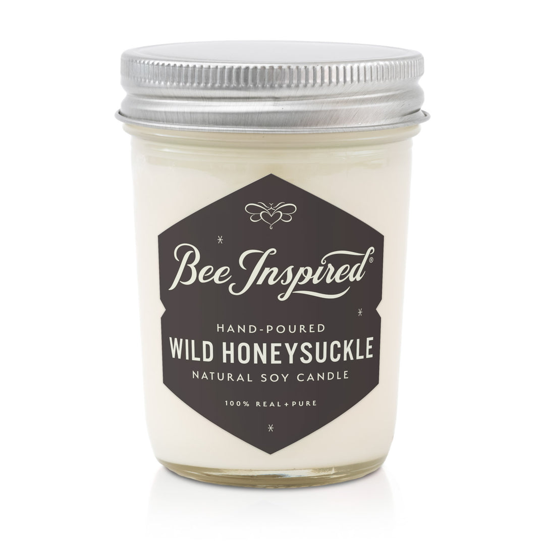 Candle jar labeled 'Bee Inspired' with 'Wild Honeysuckle' scent on a white background