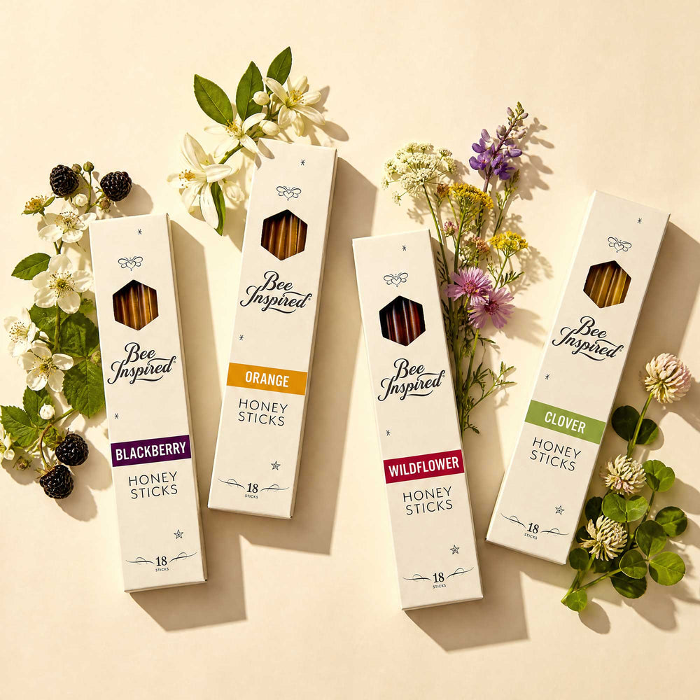 Four boxes of 'Bee Inspired' honey sticks with floral decorations on a beige background